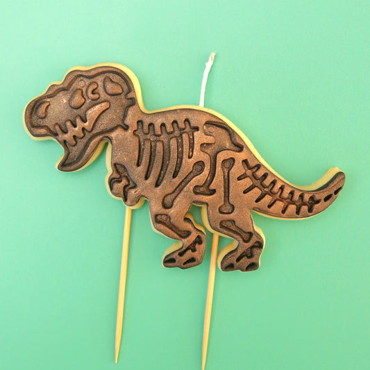 Dinosaur skeleton cake topper cookie on a green background