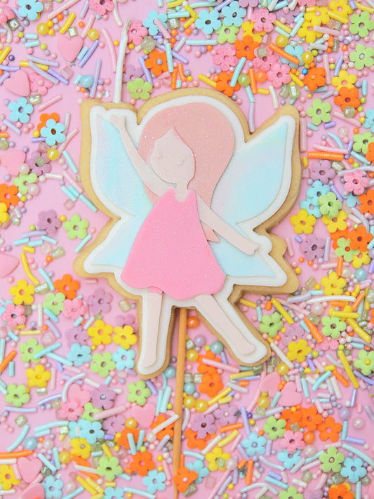 Fairy-themed edible cake topper birthday candle on a stick with colourful sprinkles in the background