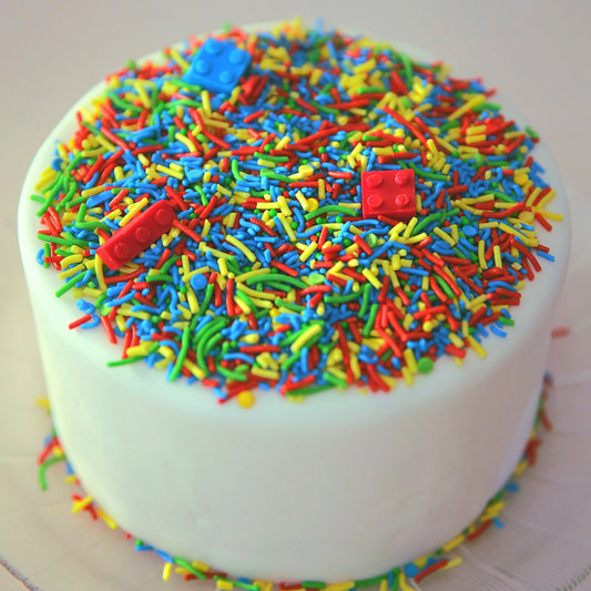 Colorful sprinkled cake with red blocks on a white background