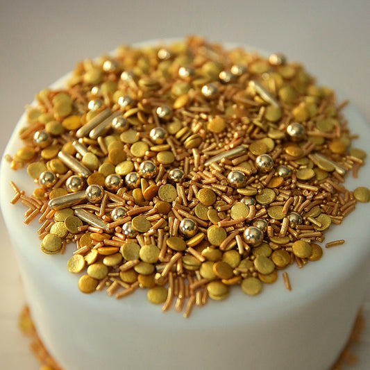 Close-up of a cake covered with gold sprinkles on a white background