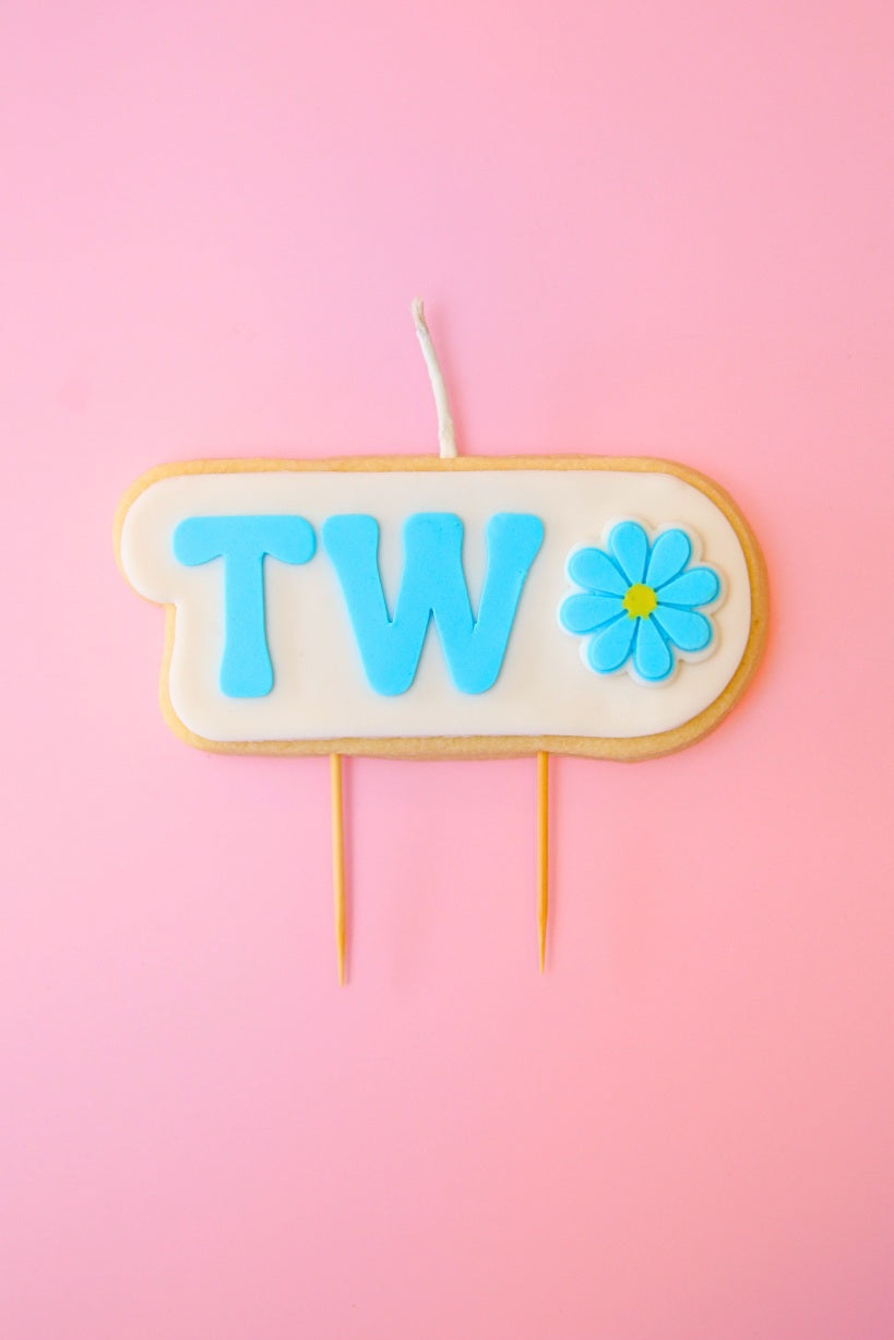 Candle with 'TWO' and a flower on a pink background