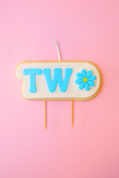 Candle with 'TWO' and a flower on a pink background