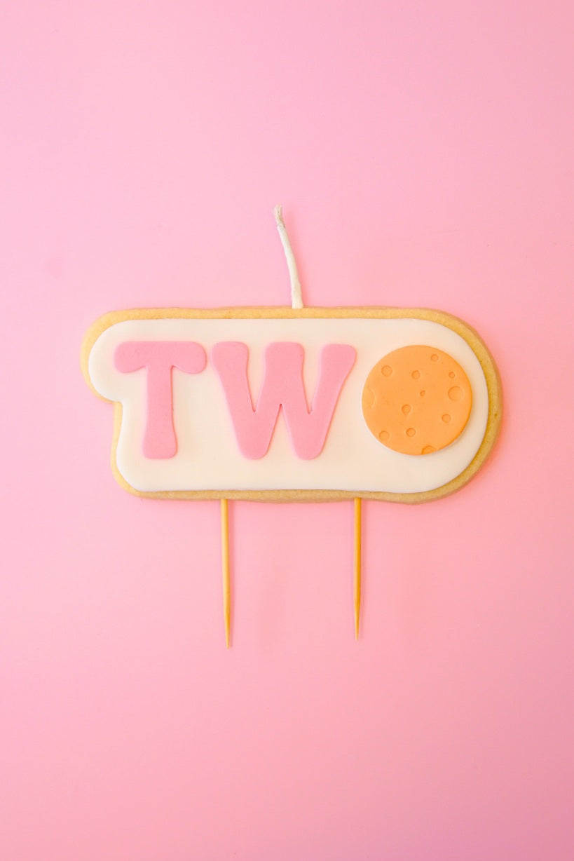 Candle shaped like the number ' TWO' on a pink background