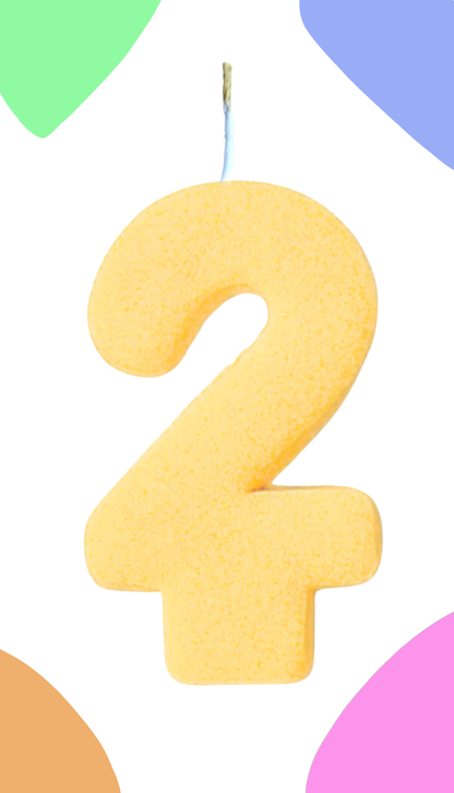Yellow number 2 cookie candle against a colorful background