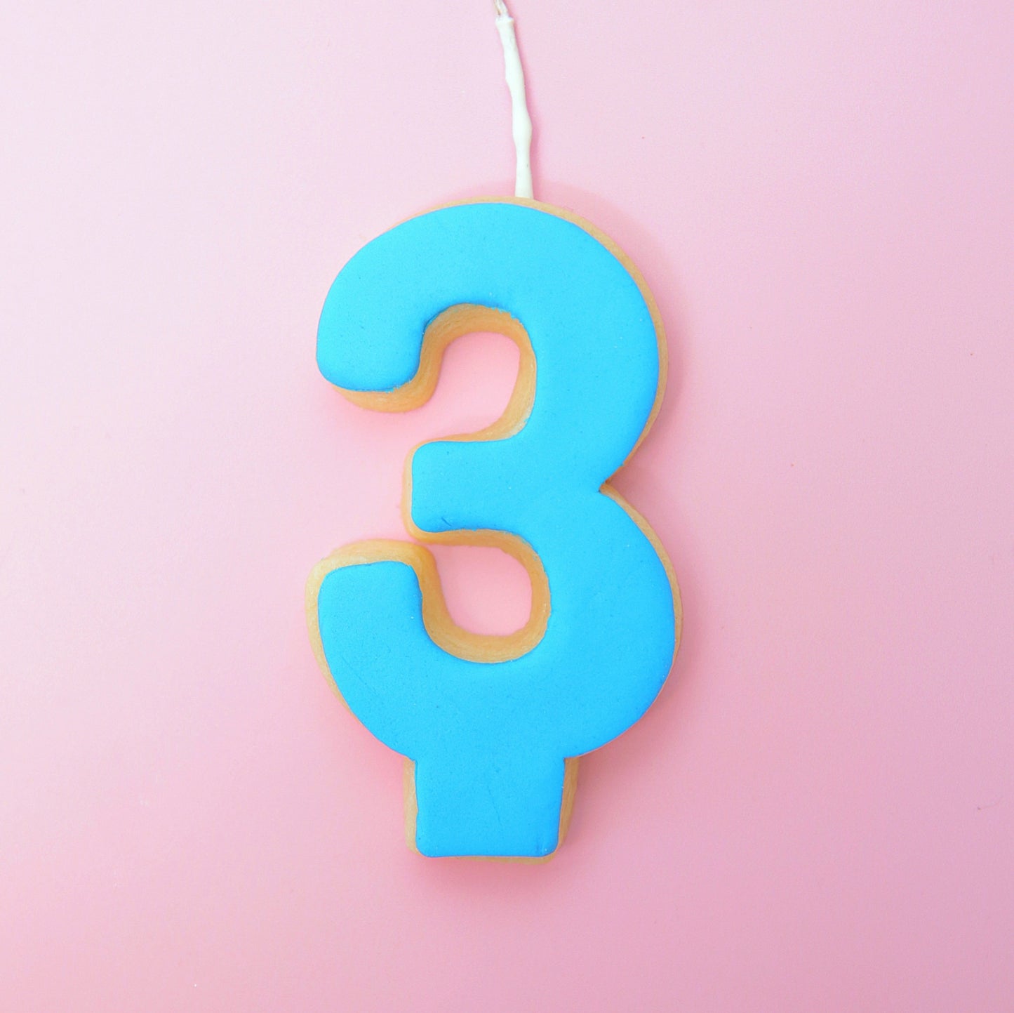 Blue number 3 cookie on a pink background