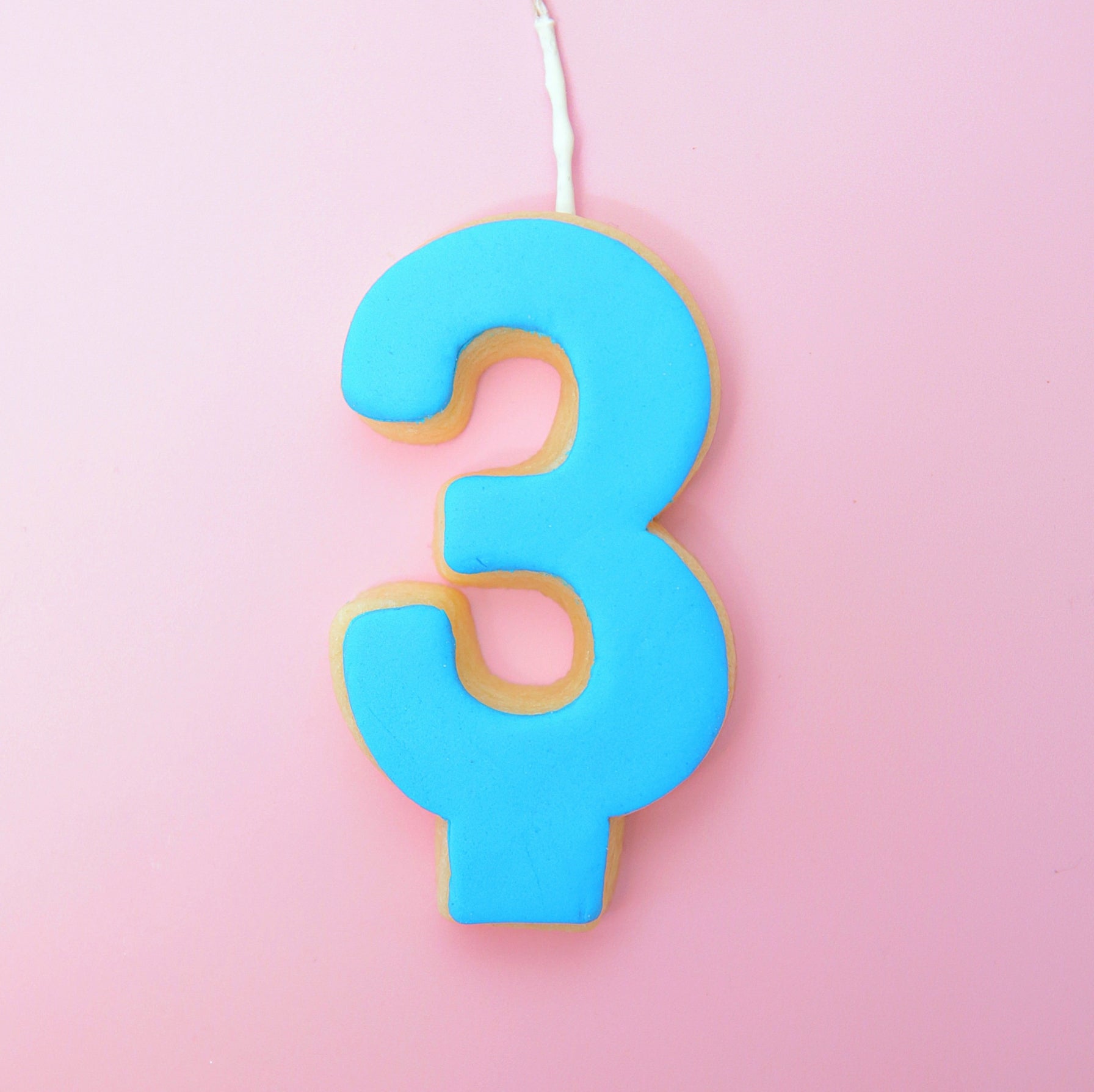 Blue number 3 cookie on a pink background