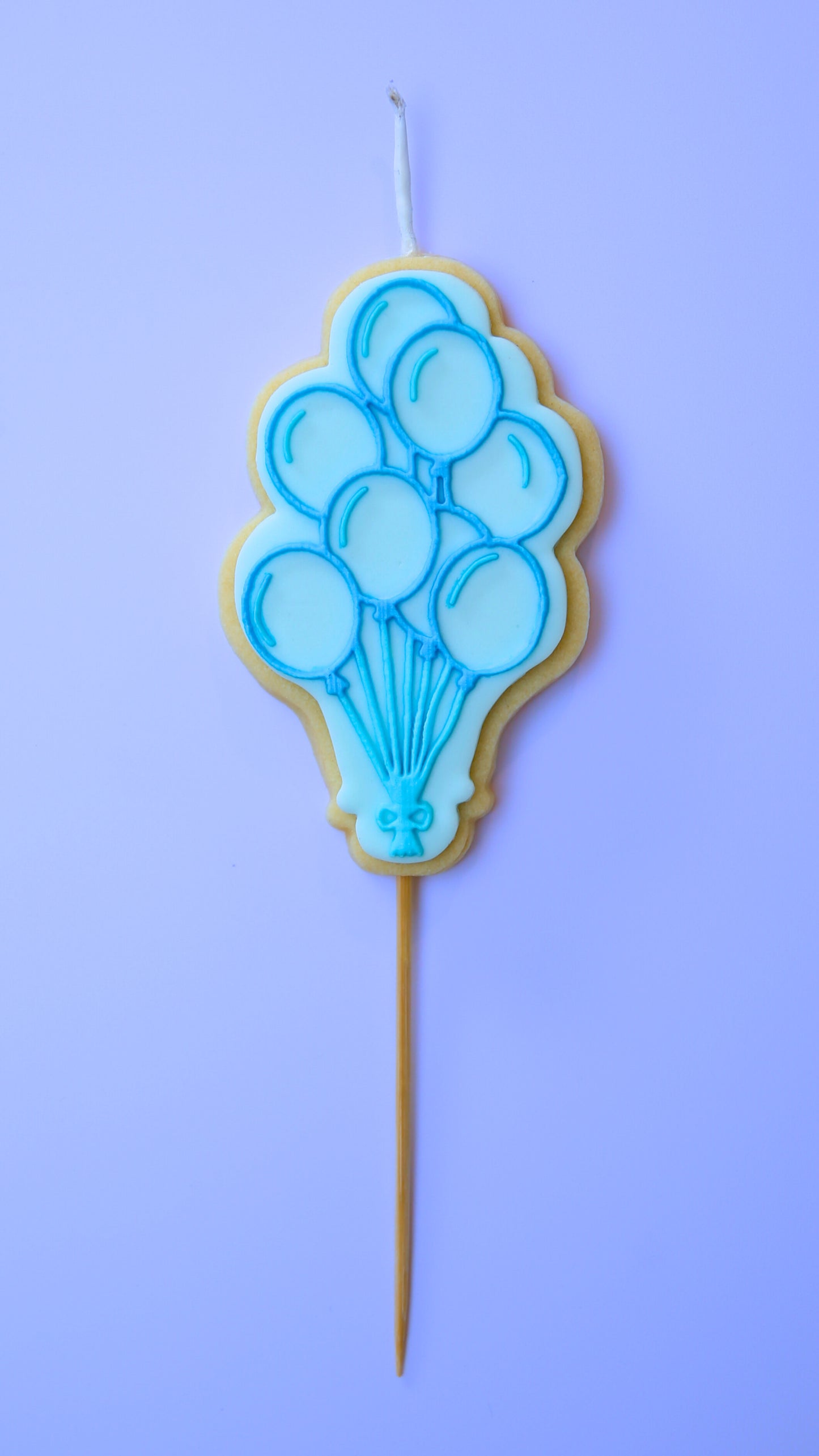 Blue Balloon-themed candle on a stick against a purple background