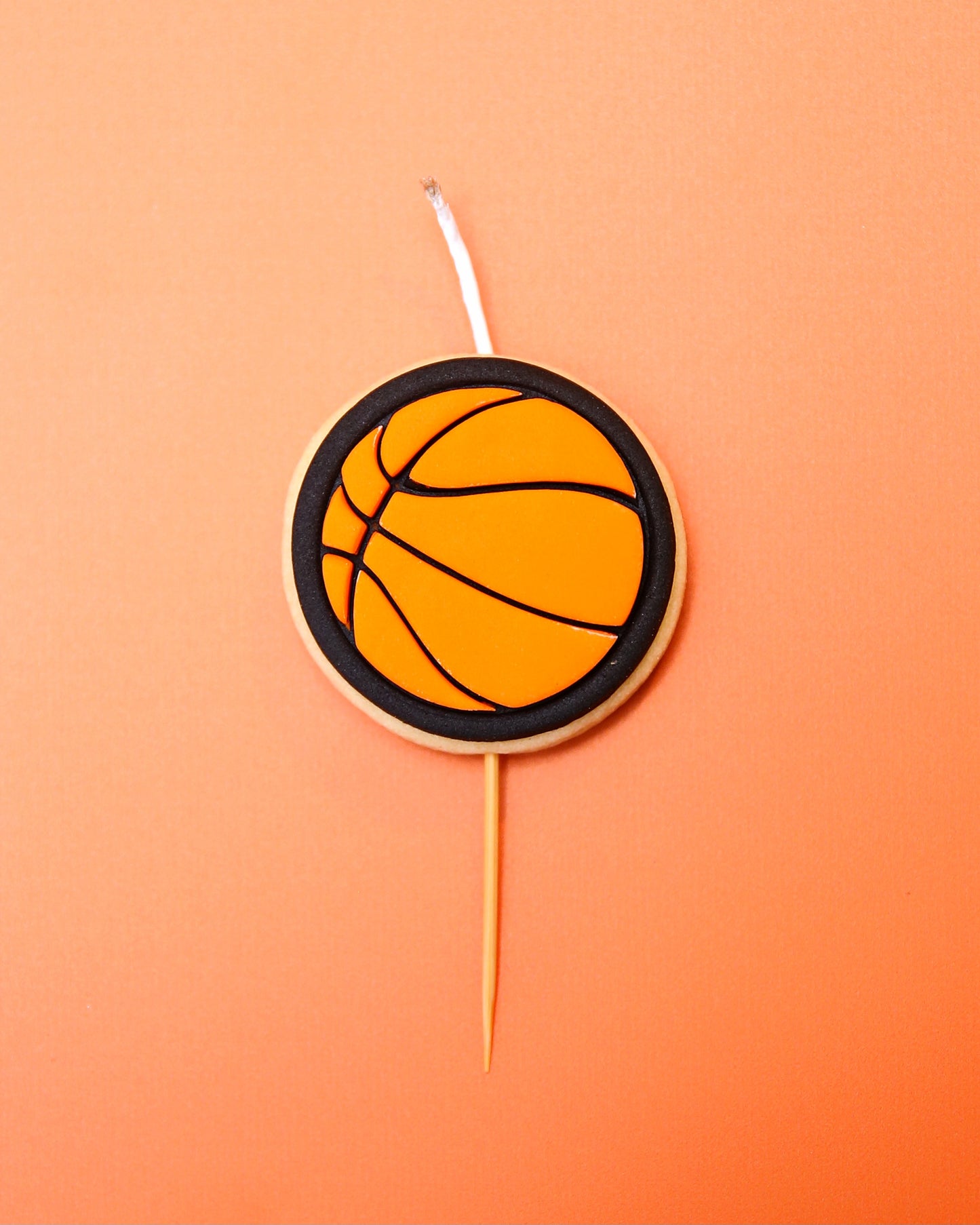 An orange basketball mini Cookie Candle on an orange background 