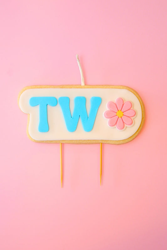 Candle with 'TWO' and a flower on a pink background