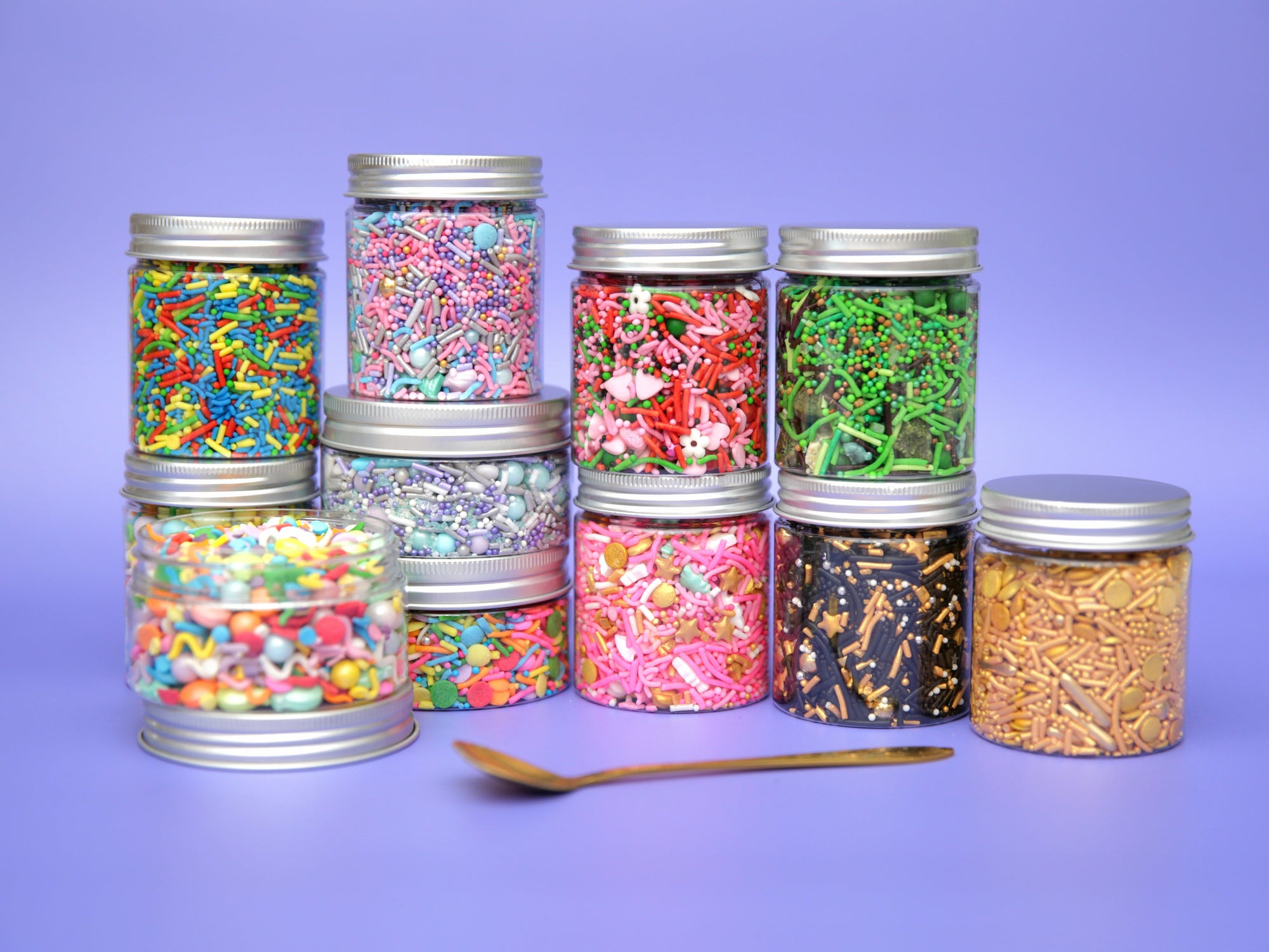 Assorted colourful jars of sprinkles on a purple background