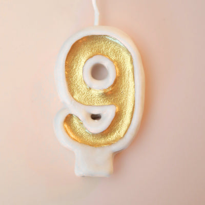 Gold number 9 candle on a pink background