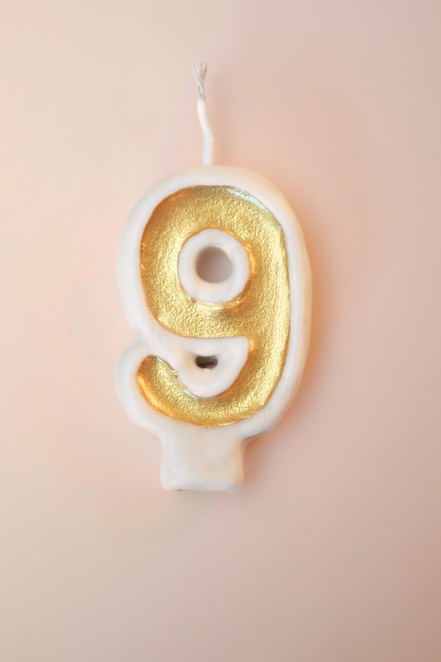 Gold number 9 candle on a pink background
