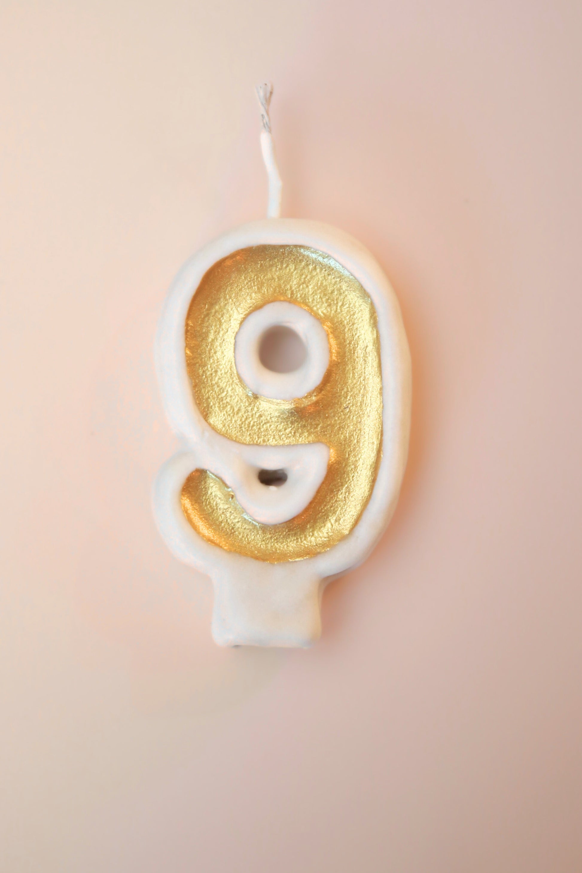 Gold number 9 candle on a pink background