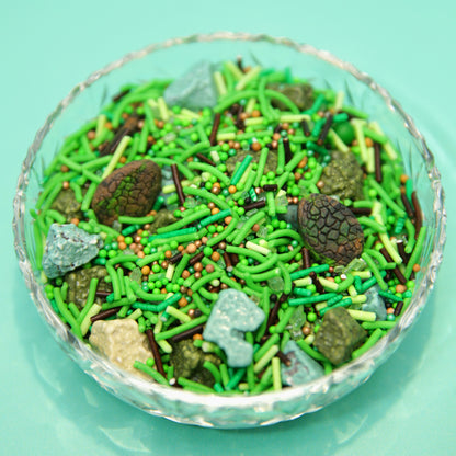 Glass bowl filled with green and brown sprinkles on a teal background