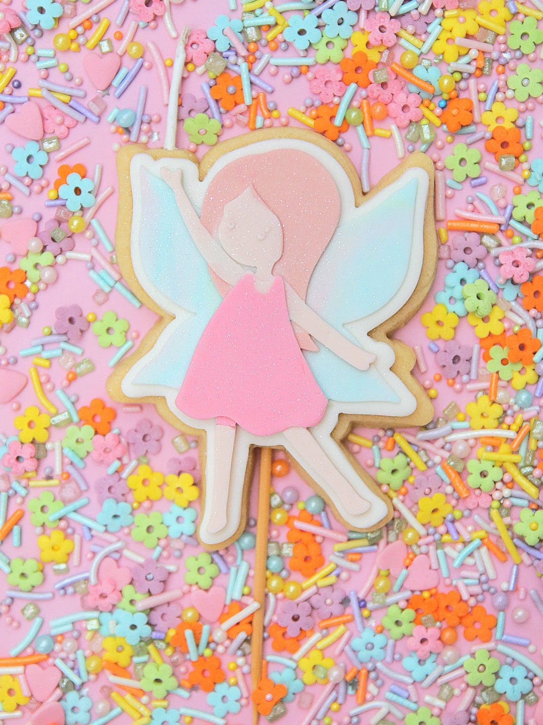 Fairy-themed edible cake topper birthday candle on a stick with colourful sprinkles in the background