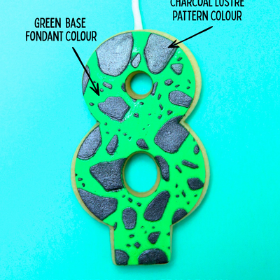 Green edible number eight birthday candle with rocky road pattern on a blue background