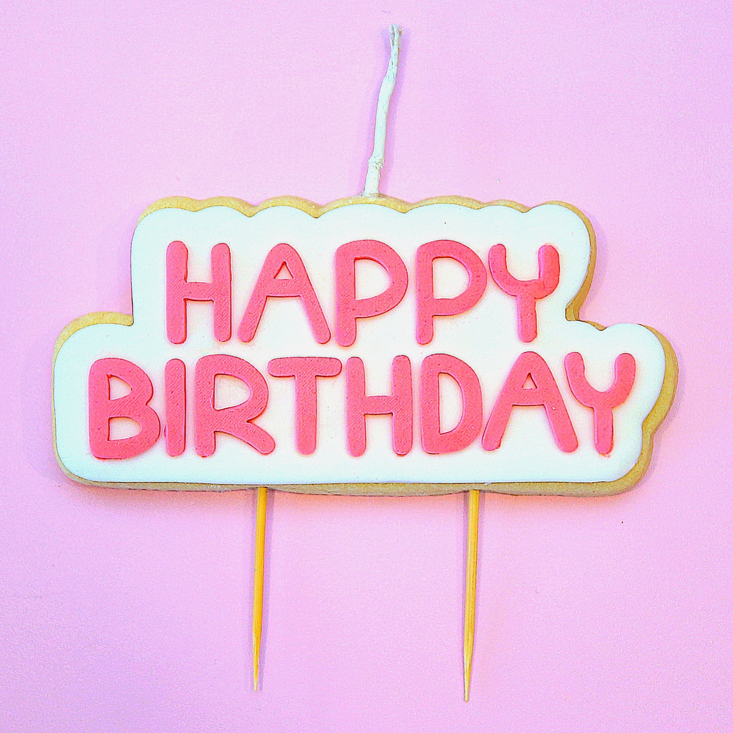 Cookie Candle with pink 'Happy Birthday' text on a pink background