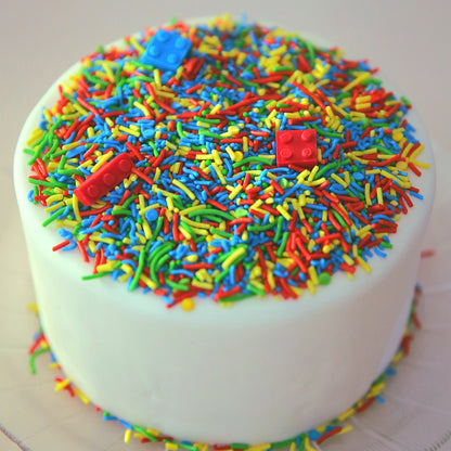Colorful sprinkled cake with red blocks on a white background