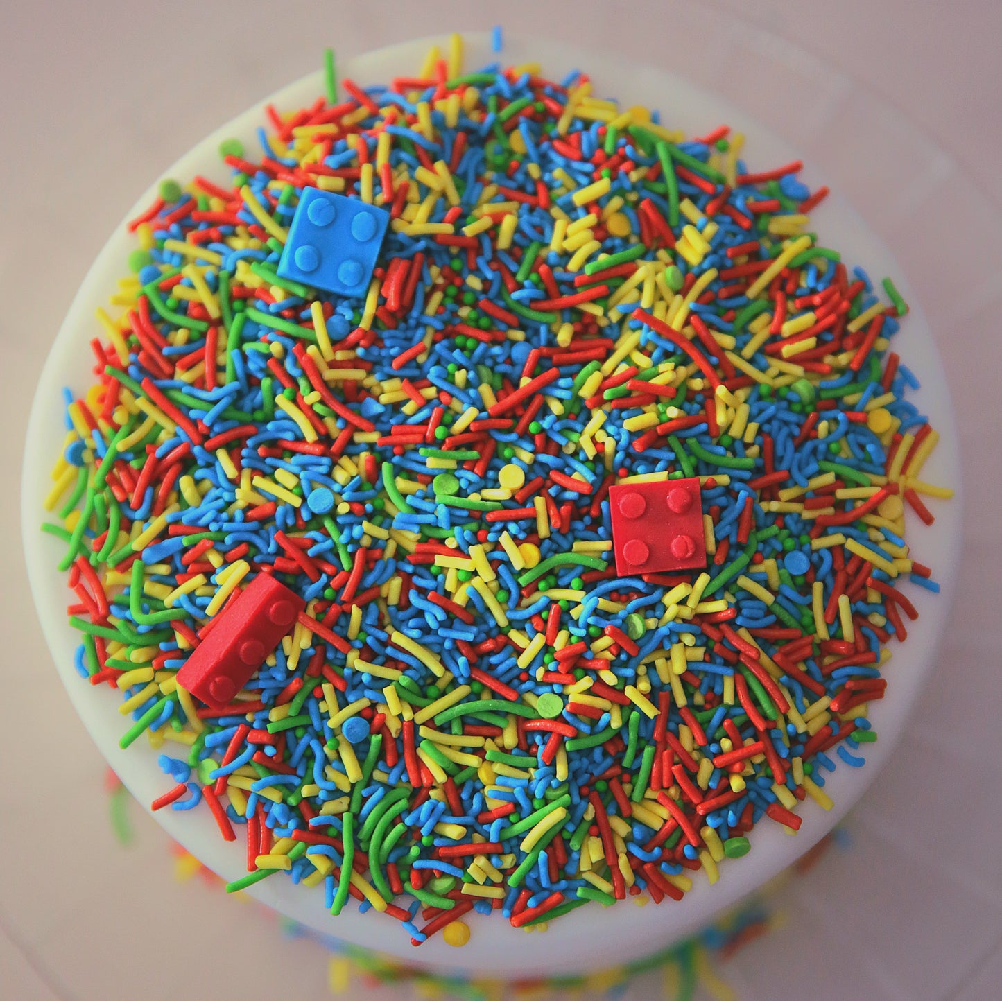 Colourful sprinkles with edible bricks on a white cake