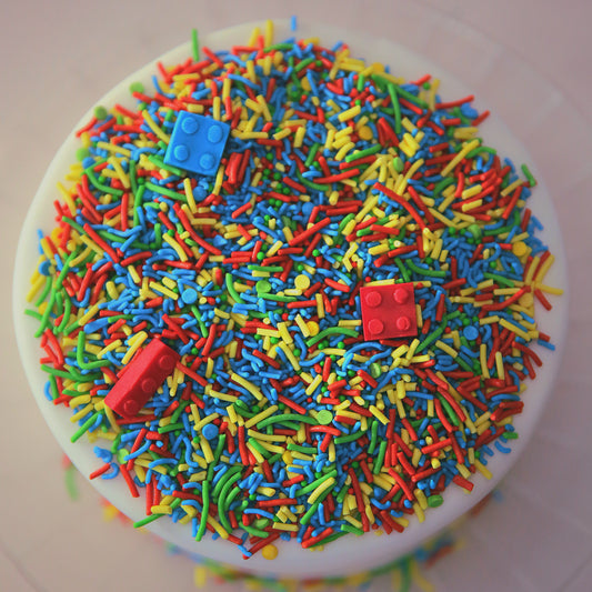 Colourful sprinkles with edible bricks on a white cake