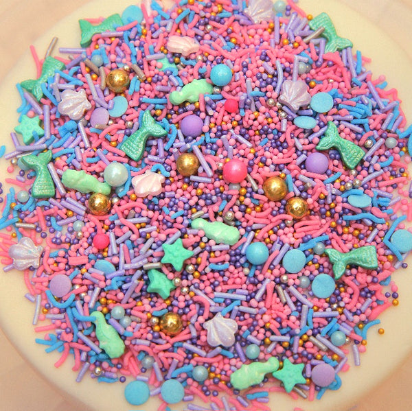 Colorful Mermaid sprinkles on a cake with various shapes and colors.