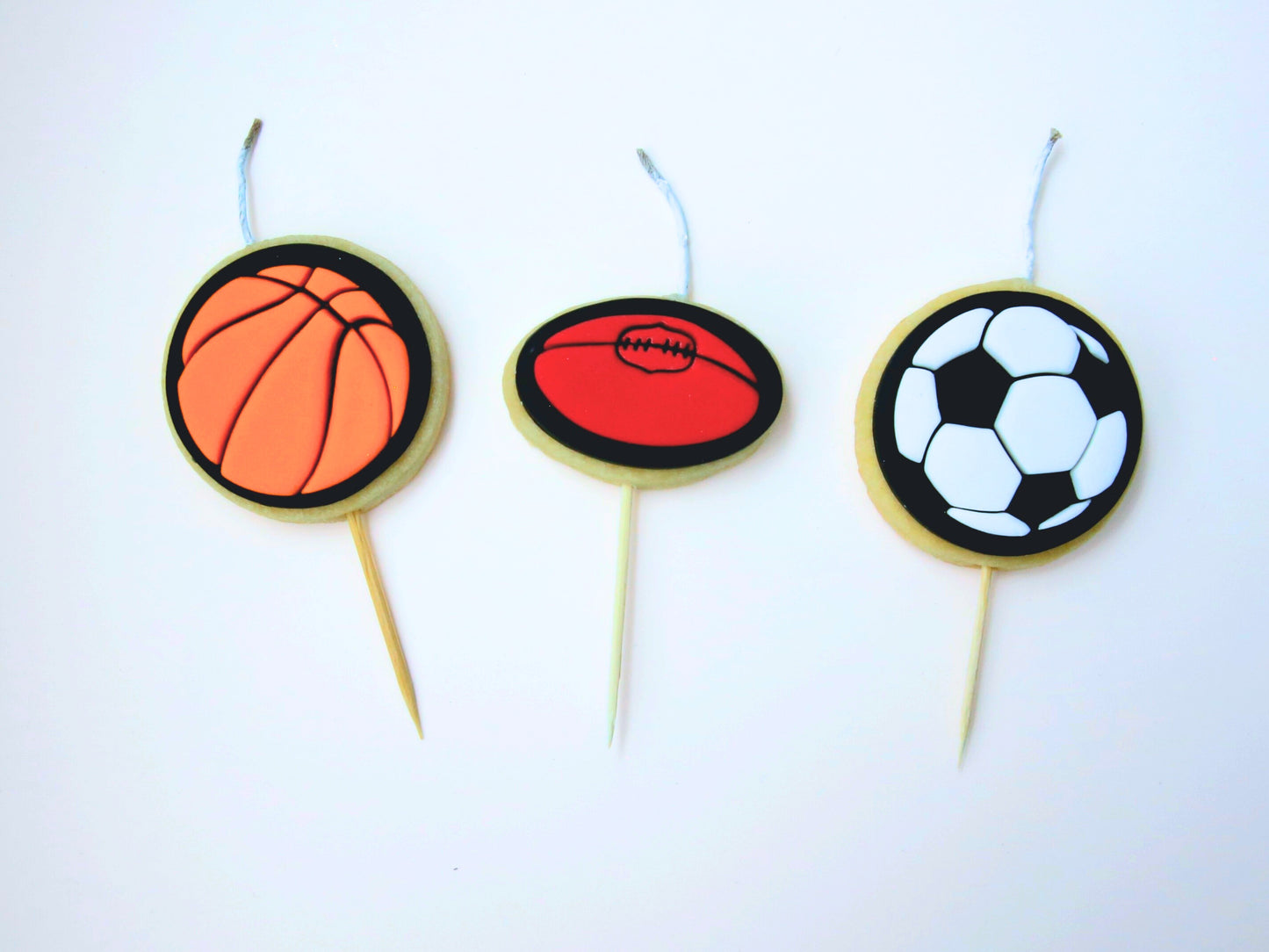 Small cookie candles depicting a basketball, football and soccer ball.