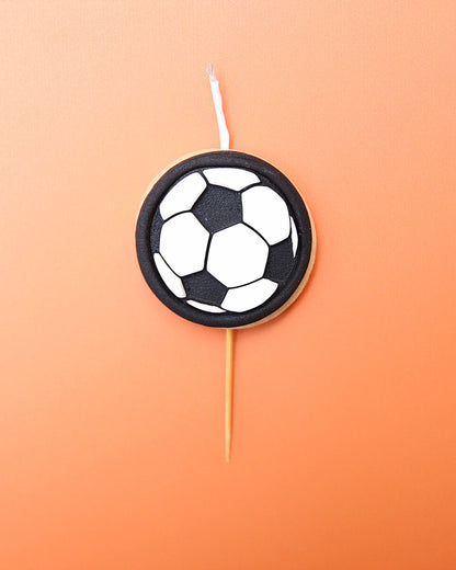 A Mini soccer ball cookie candle on an orange background 