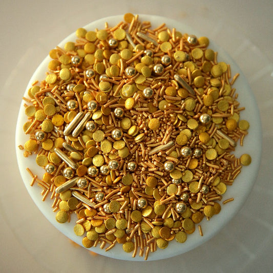 Assorted gold-colored sprinkles on a white cake 