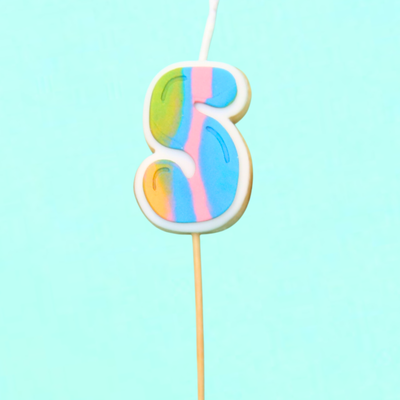 Colorful number 5 candle on a stick against a light blue background
