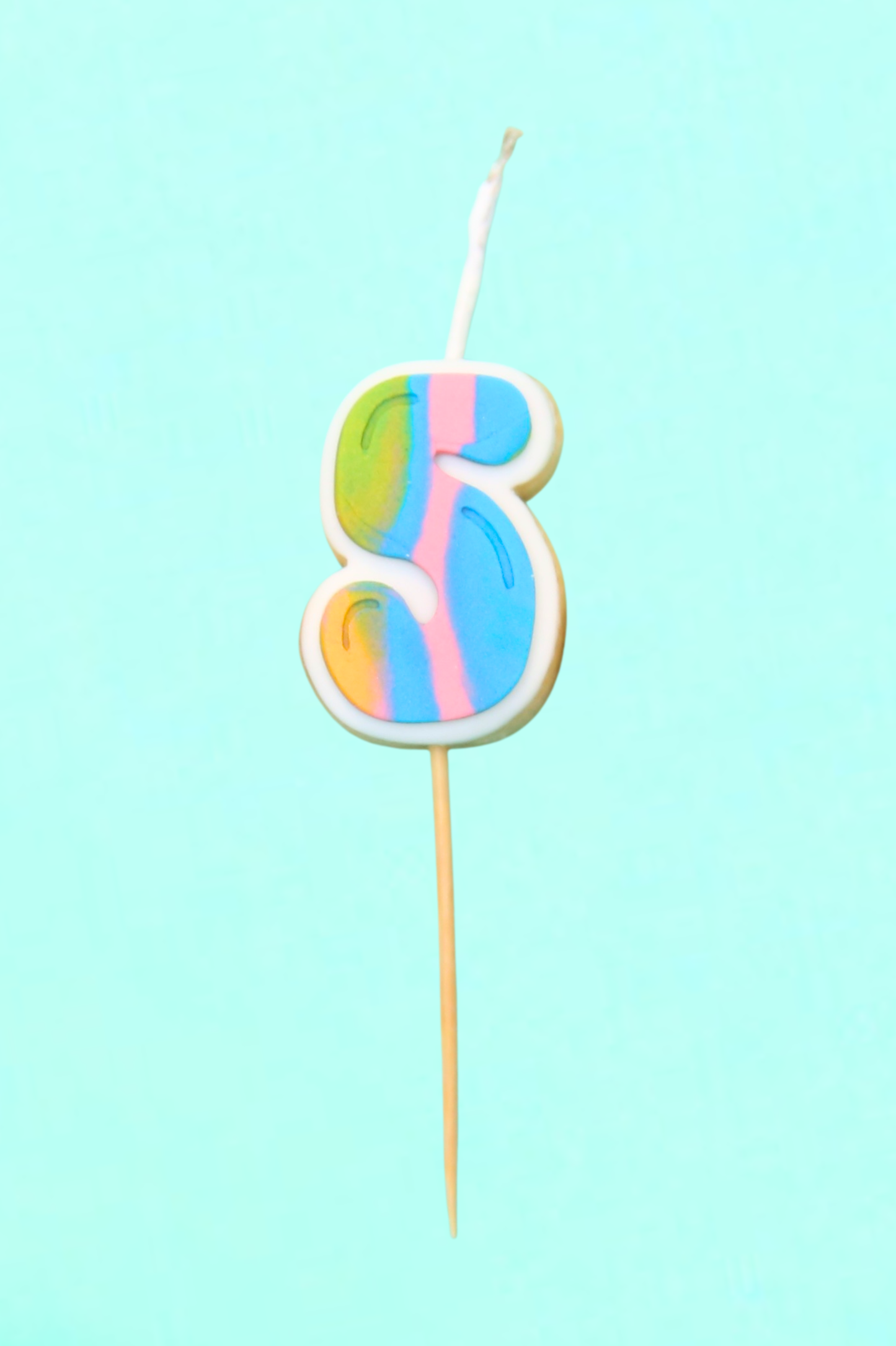 Colorful number 5 candle on a stick against a light blue background
