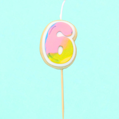Colorful number 6 birthday candle on a light blue background