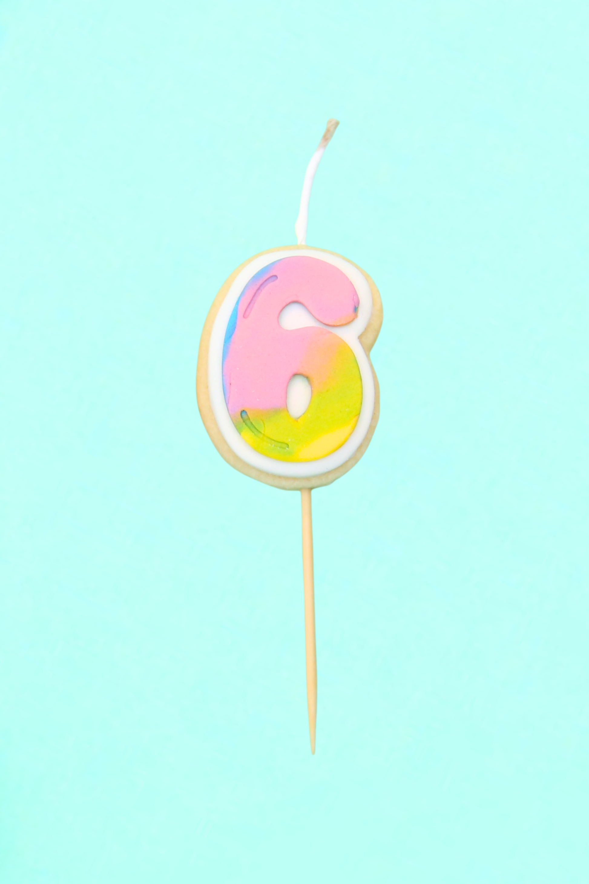 Colorful number 6 birthday candle on a light blue background