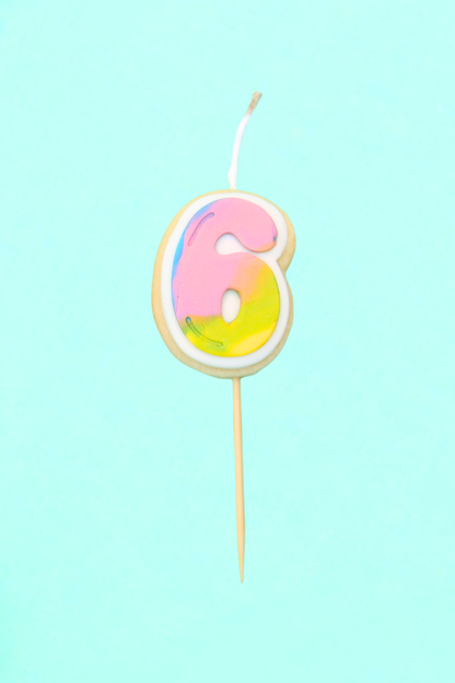 Colorful number 6 birthday candle on a light blue background