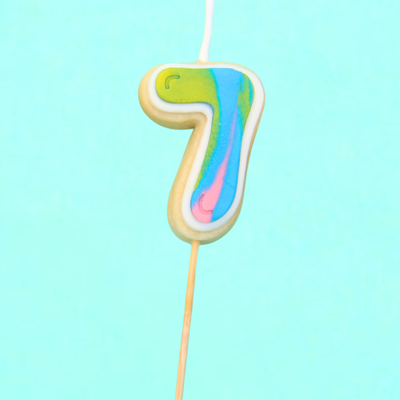 Colorful number 7 cookie candle on a light blue background