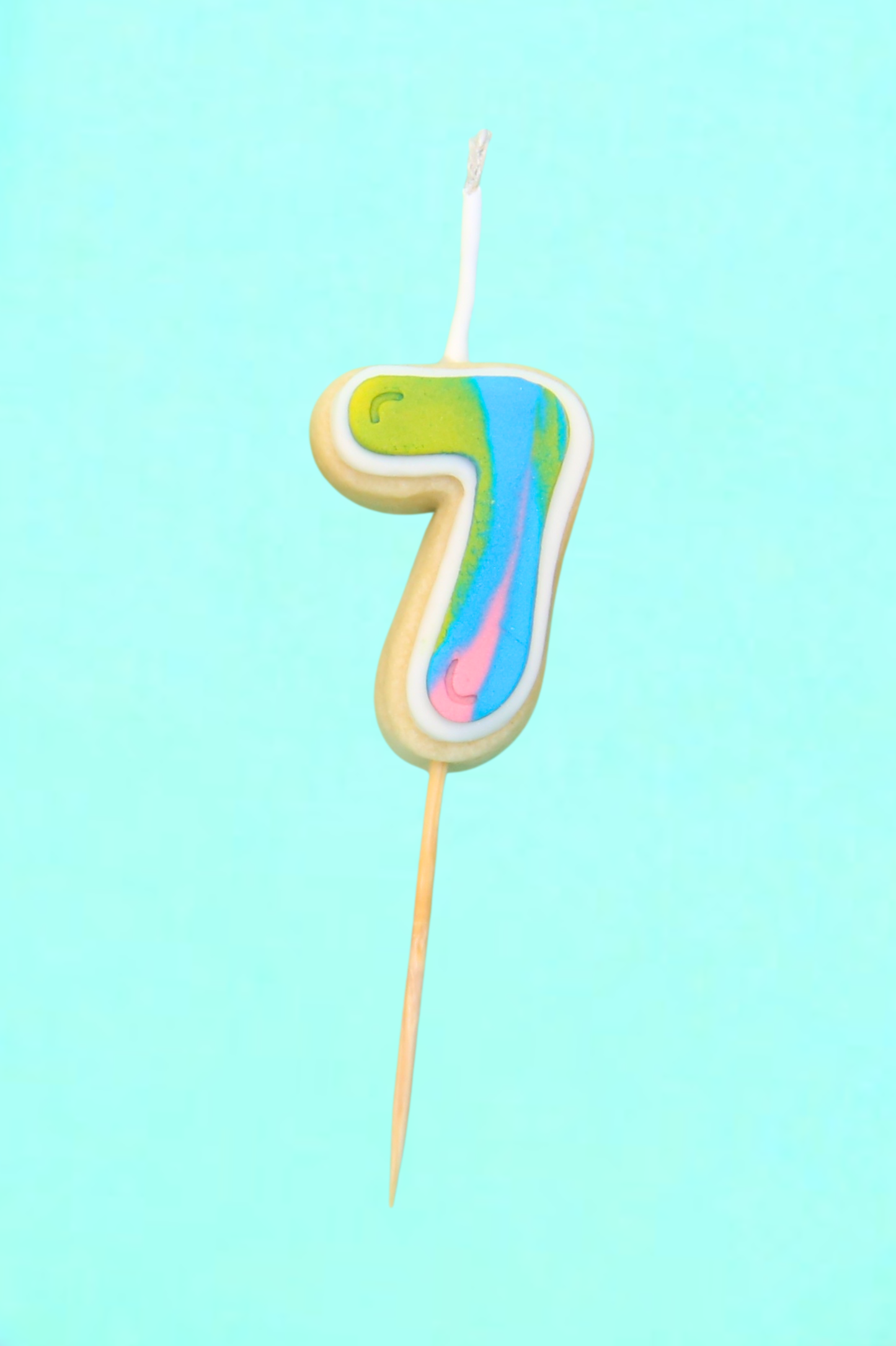 Colorful number 7 cookie candle on a light blue background