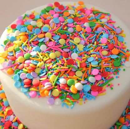 White cake covered with colorful sprinkles on a white background