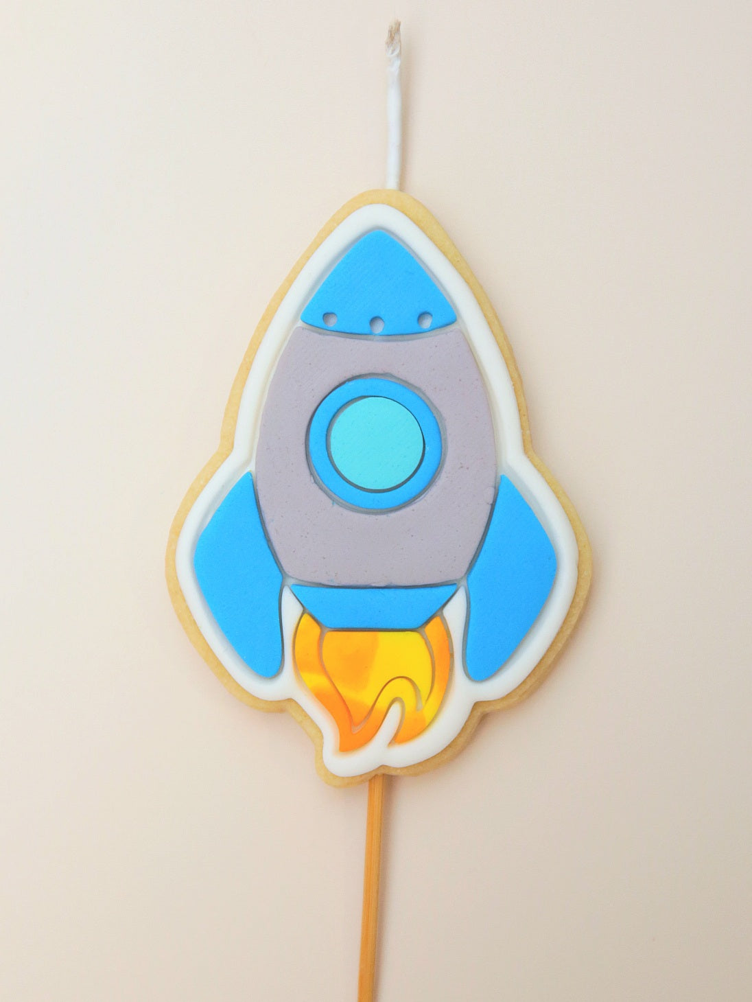 Decorative cookie shaped like a rocket on a stick with blue and gray design.