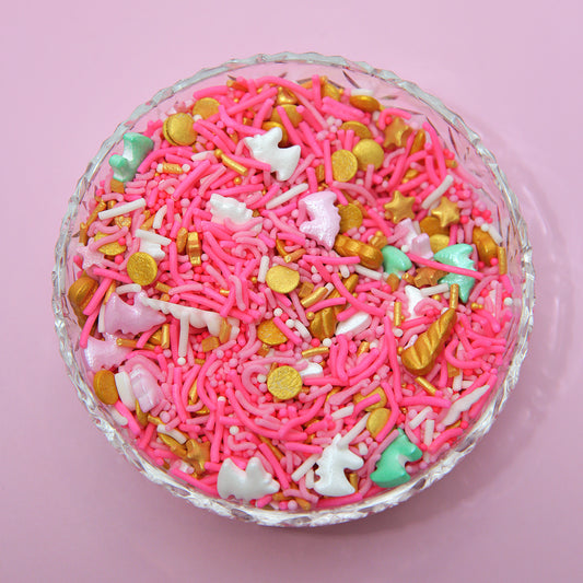 Colorful sprinkles with pink, gold, and white on a pink background