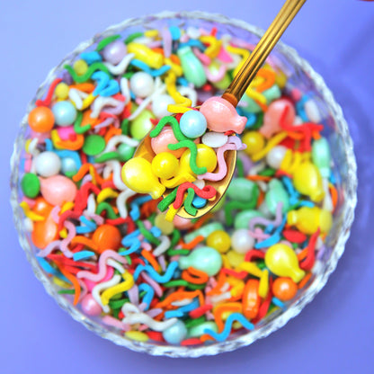 A brightly coloured bowl of wiggly rainbow confetti sprinkles with sugar balloons
