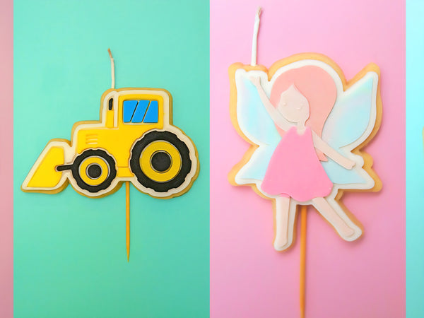 Two cake candles, one shaped like a yellow tractor and the other like a fairy, on a colourful background.