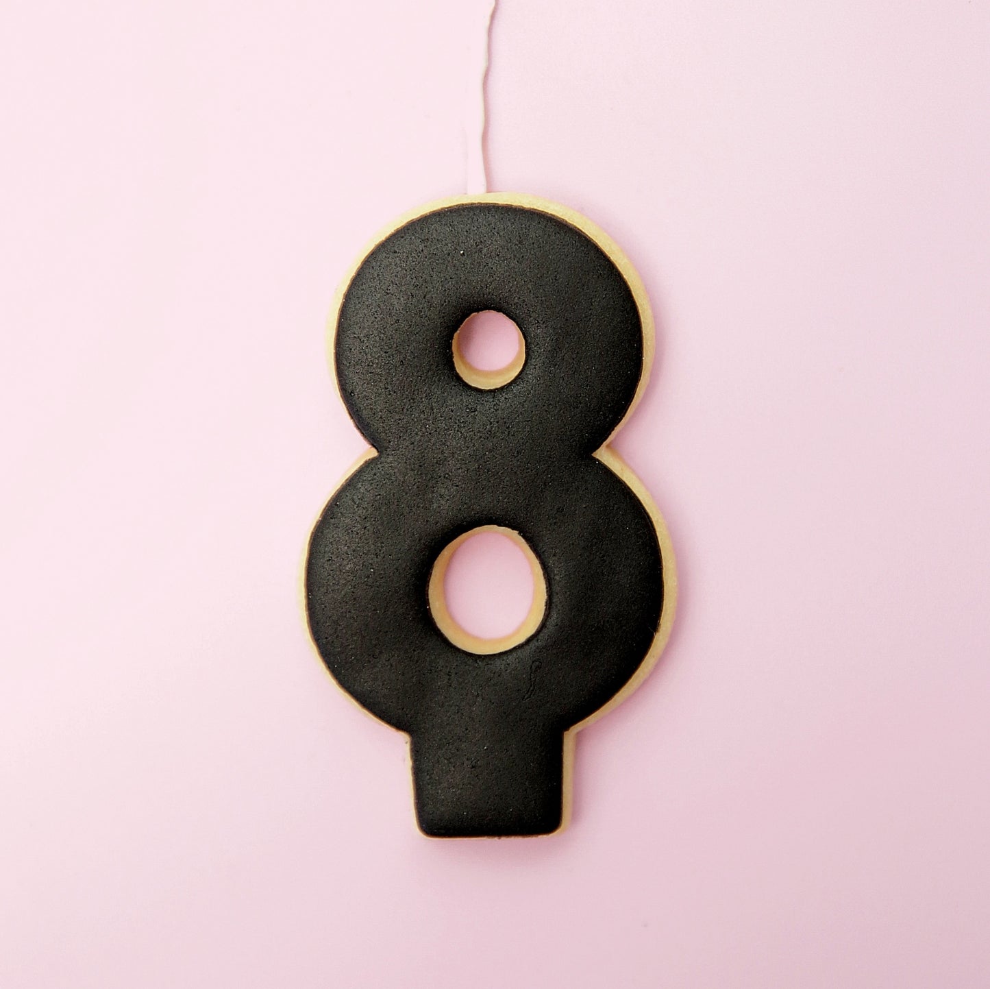 Black number 8 cookie on a pink background