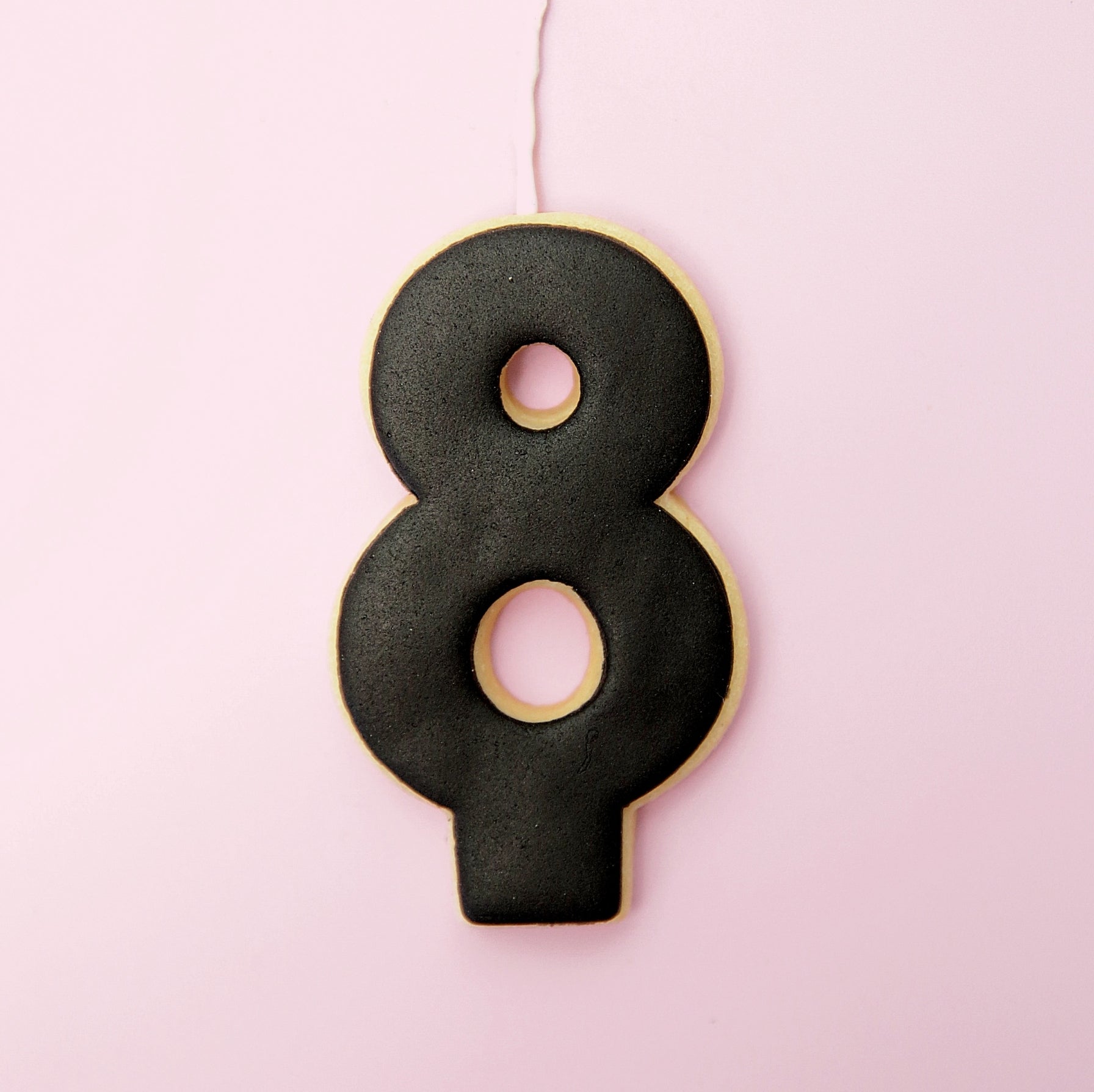Black number 8 cookie on a pink background