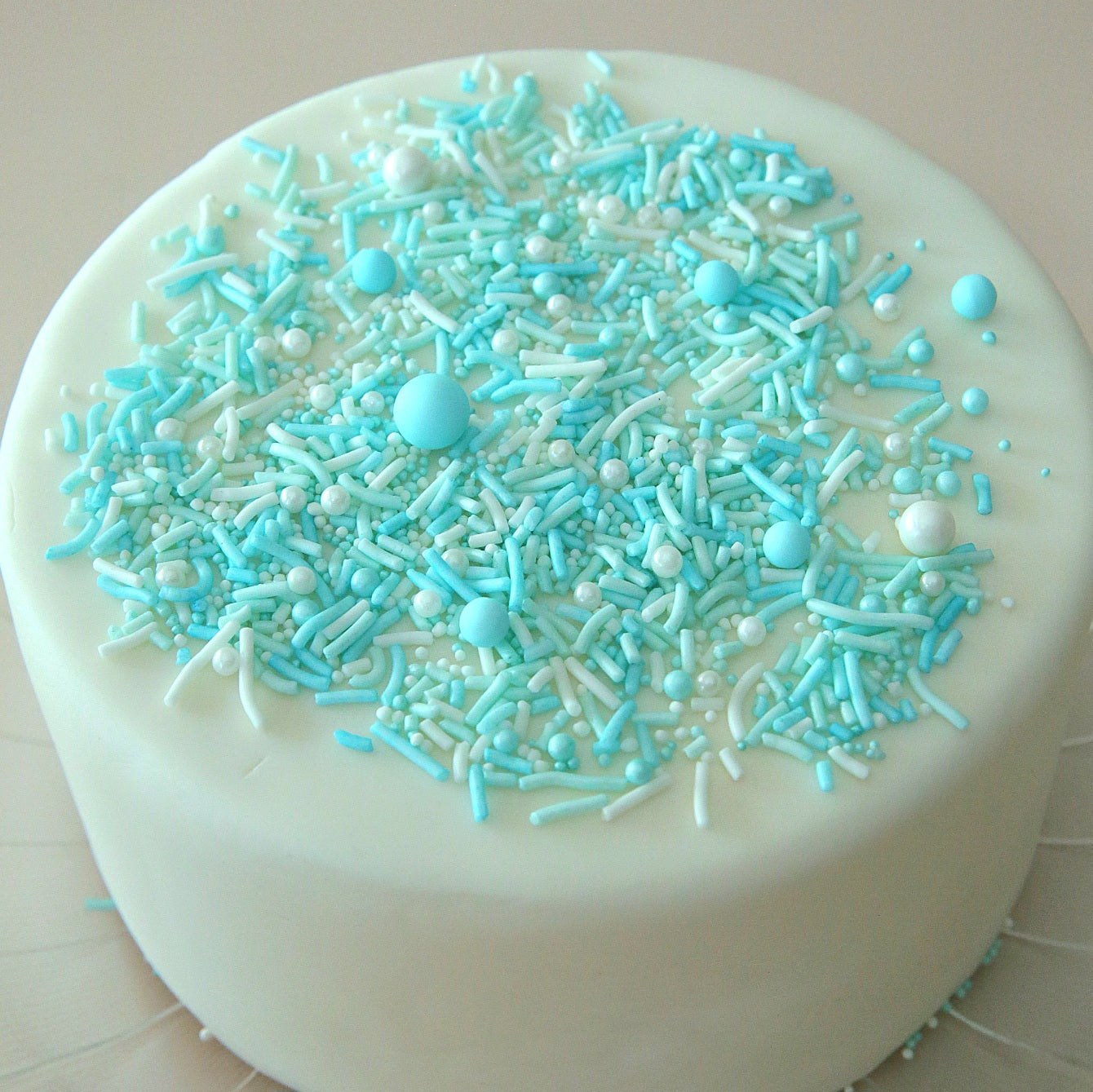 White cake with blue and white sprinkles on a white background