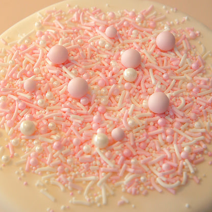 Close-up of a cake covered in pink and white sprinkles on a beige background