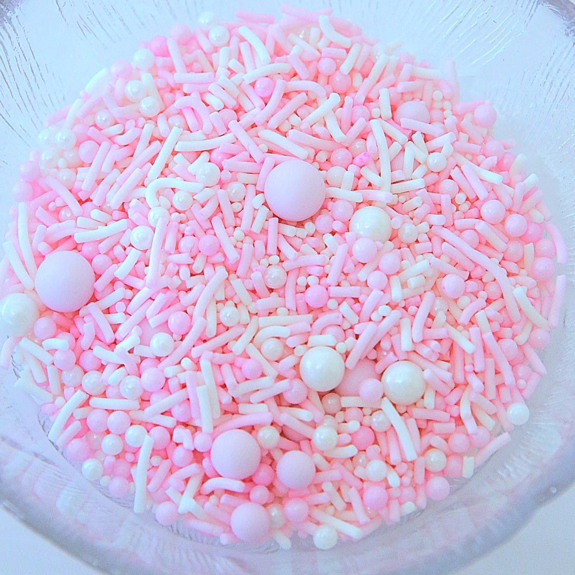 Pink and white sprinkles in a clear bowl