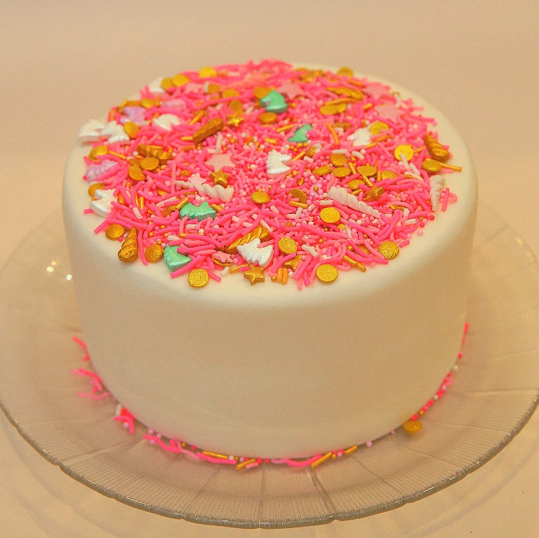 White cake with pink and multicolored sprinkles on a clear plate.