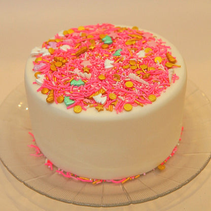 White cake with pink and multicolored sprinkles on a clear plate.