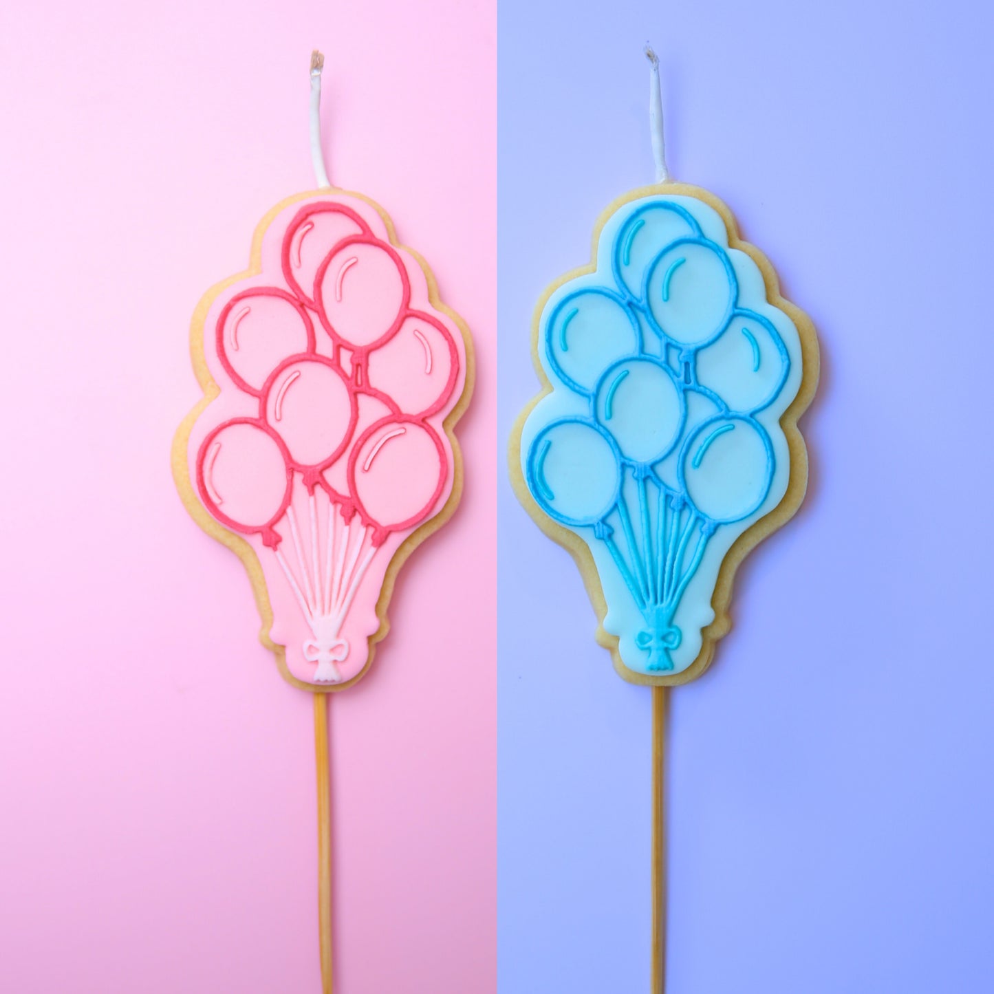 Two balloon-shaped cookie candles, one pink and one blue, on a two-tone pink and purple background.