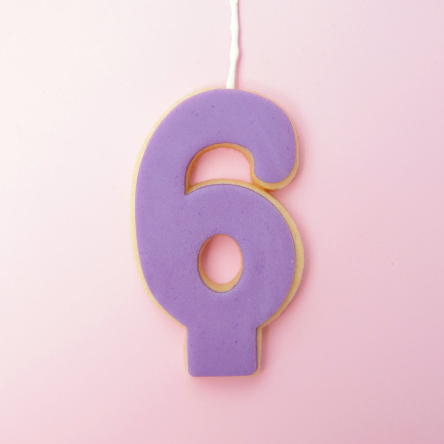 Purple number 6 cookie on a pink background