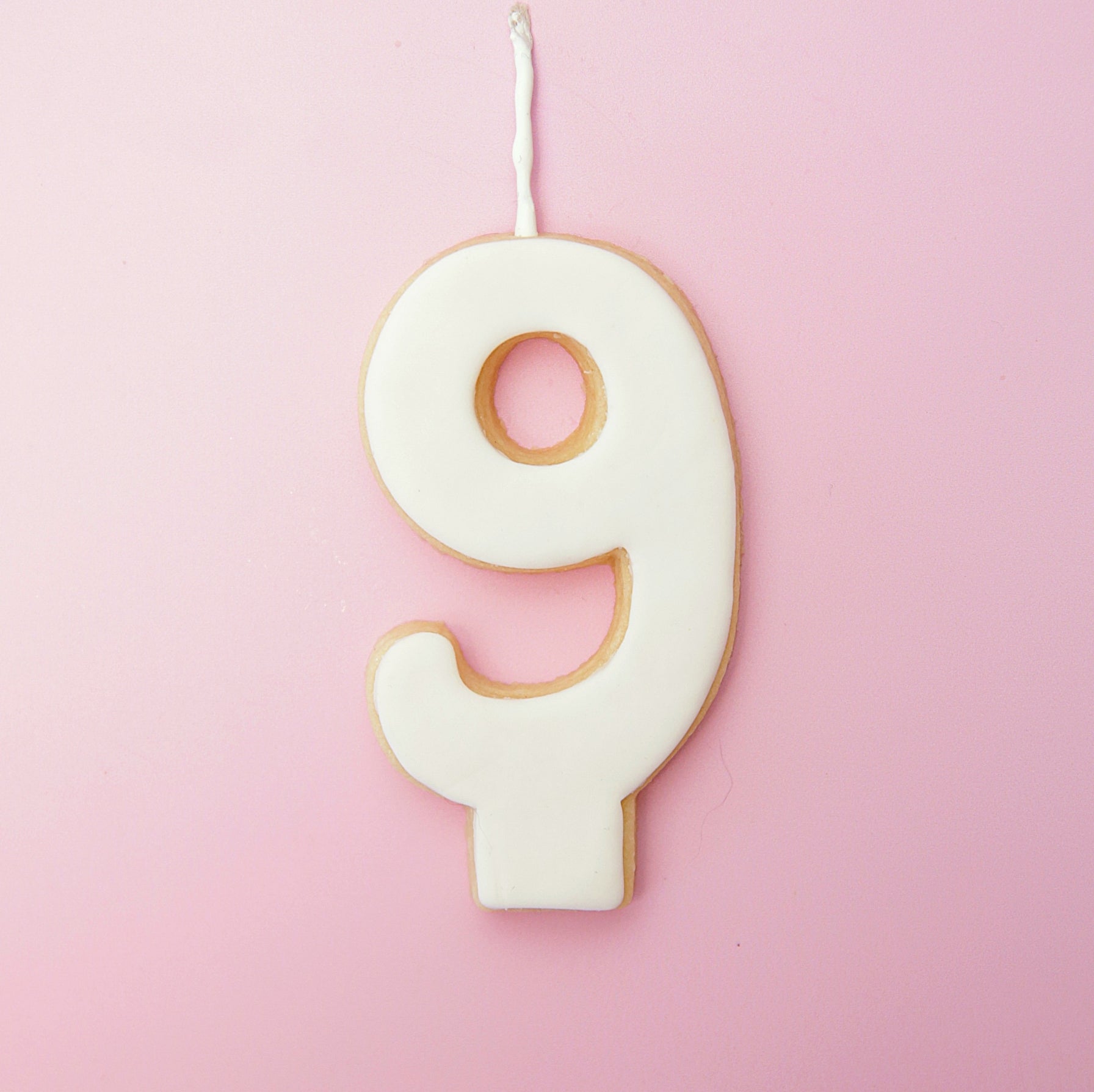White Number 9 cookie decoration on a pink background